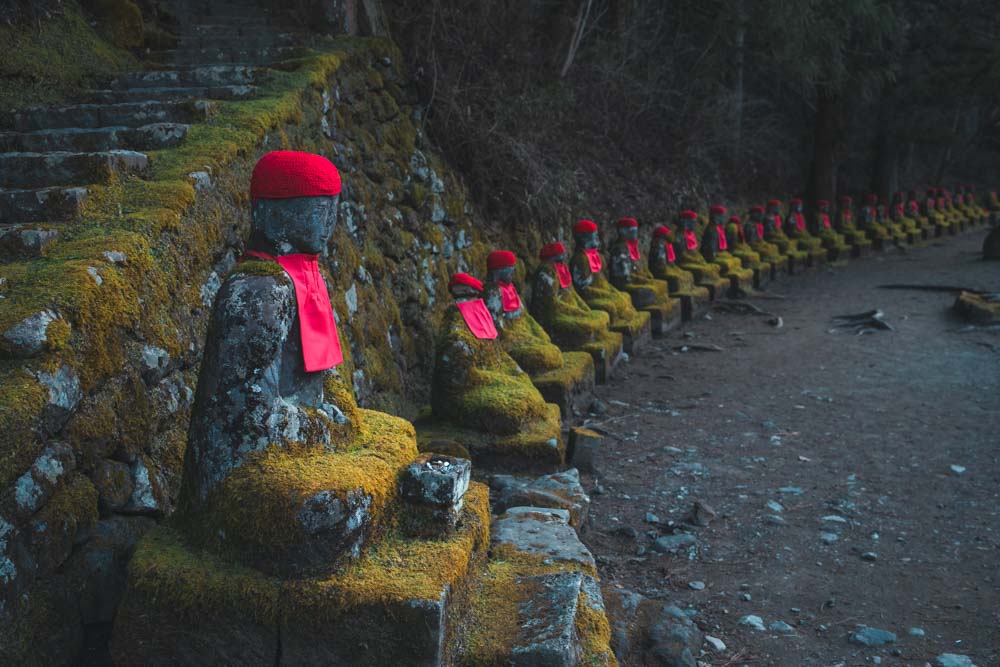 Statue con sciarpina e cappellino rosso a Kanmangafuchi Abyss a Nikko