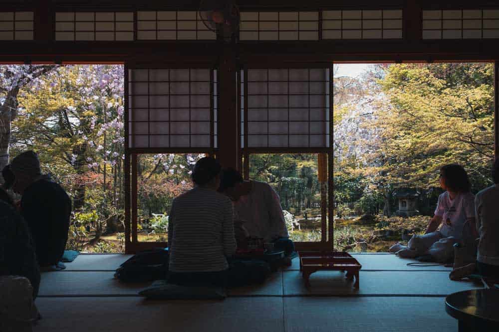 Ristorante tradizionale nel tempio Rioanji a Kyoto con persone che mangiano sedute per terra sui tatami guardando il giardino